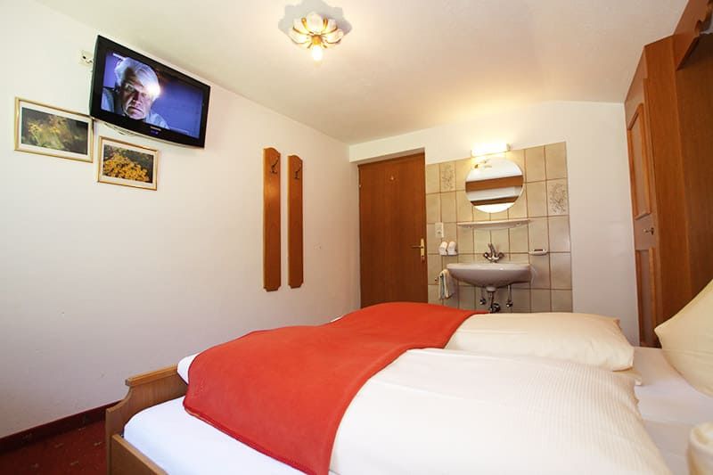 Doppelbettzimmer mit Waschbecken und SAT-TV